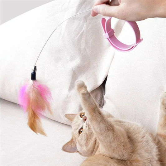 Gray cat playing with a pink feather teaser toy, enjoying interactive playtime