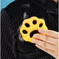 Orange paw-shaped pet hair remover removing dog and cat hair from black clothing fabric