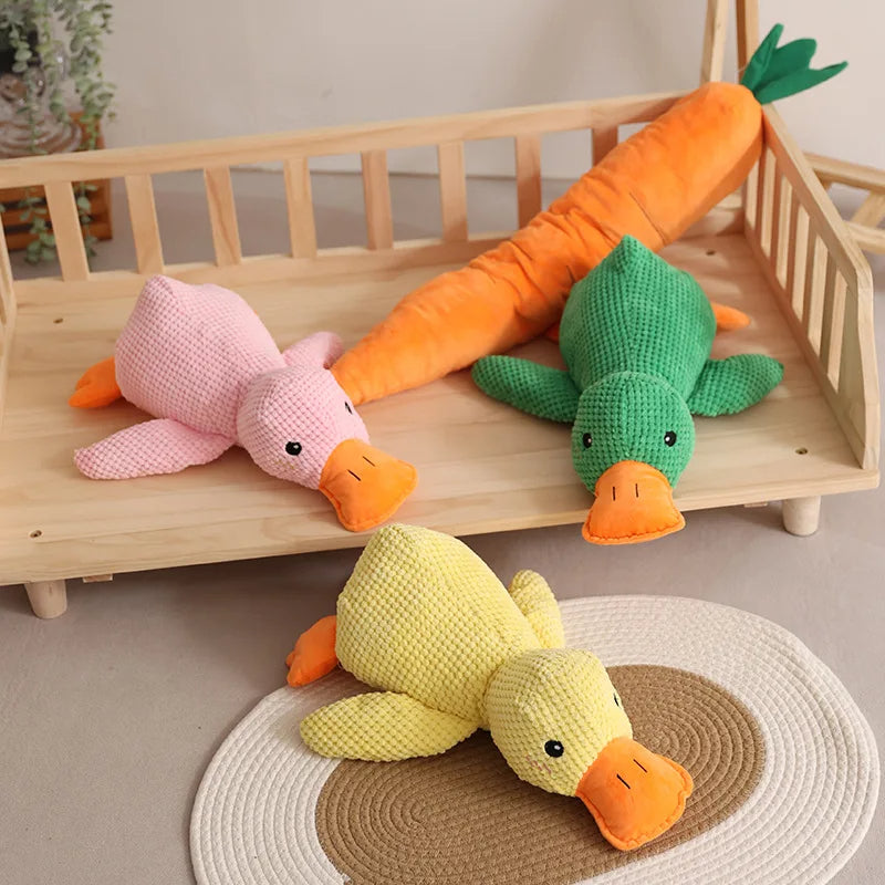 Plush squeaky duck pet toys in green, pink, and yellow colors displayed in a cozy indoor setting.