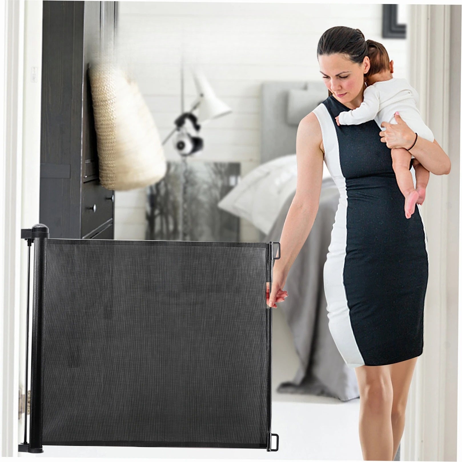 Retractable dog gate used as a child safety barrier while a parent holds a baby in a home hallway