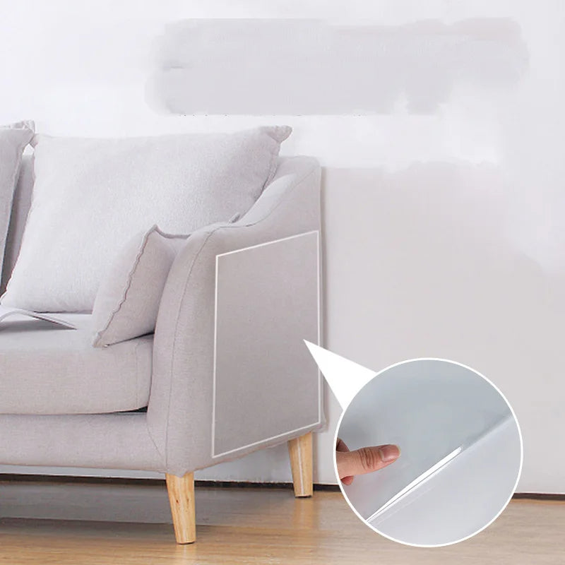 Clear self-adhesive cat scratch furniture protector applied to the side of a fabric sofa to prevent claw damage